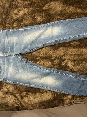 Replay ljusblå jeans, storlek 12A - Säljer ett par ljusblå Replay jeans med snyggt slitna detaljer och klassiska bakfickor med mörkblå söm. Modellen har rak passform och är tillverkad i mjukt jeanstyg som sitter skönt hela dagen.