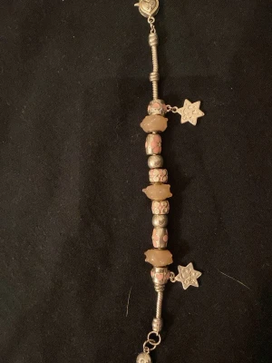 Pandora armband med blommiga berlocker - Unikt Pandora armband i silver med flera berlocker i rosa och beige toner. Armbandet har blommönstrade detaljer, stjärnformade hängen och ett hjärtformat lås. Perfekt accessoar för dig som gillar personliga smycken med fina detaljer. Är ej säker om det är Pandora men tror det 💘PRIS GÅR ATT DISKUTERA