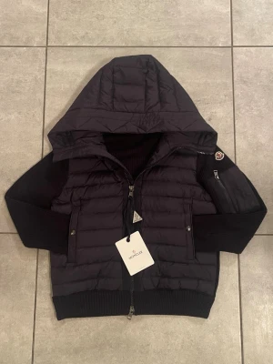 Navy blue Down Zip-Up Cardigan Från Moncler - Säljer en Navy Down Zip-Up Cardigan Från Moncler. Bilderna ser den ut som den är svart men är i självavärket marineblå. Storlek M men passar bättre som S. Nfc funkar inte. Nyskick. Priset är inte hugget i sten.