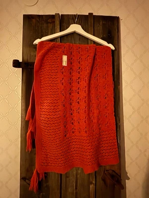 Orange stickad halsduk / sjal från Odd Molly - Säljer en orange stickad halsduk/ sjal från Odd Molly med snyggt hålmönster och fransar i nederkant. Västen har en öppen design och är perfekt för lager på lager. Supersnygg detalj till din outfit!