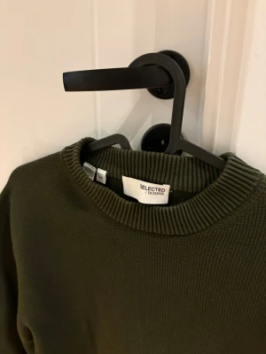 Mörkgrön stickad tröja Selected Homme - Säljer en mörkgrön stickad tröja från Selected Homme. Tröjan har rund halsringning, ribbade muddar och lång ärm. Perfekt för lager på lager under höst och vinter. Enkel och stilren design som funkar till det mesta.