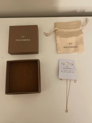Guldhalsband Mockberg bokstav H - Säljer ett stilrent guldhalsband från Mockberg med bokstaven H dekorerad med små stenar. Kedjan är tunn och elegant, och halsbandet kommer i original ask och i sidenpåse. Har aldrig använt har bara prövat, helt nytt skick!🩷