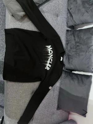 Svart sweatshirt från Moncler - Säljer en svart sweatshirt från Moncler med stort vitt tryck på bröstet där det står 'MONCLER' i en cool drip-effekt. Tröjan har rund hals, långa ärmar och en liten Moncler-logga på ena ärmen. Perfekt för dig som gillar  och vill ha något stilrent men ändå unikt.