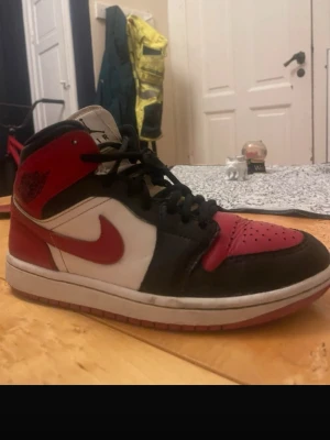 Nike Air Jordan 1 svart/röd/vit - Säljer ett par klassiska Nike Air Jordan 1 med lite skavanker på under sidan e det lite slitet 
