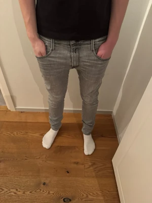 Replay ljusgrå  jeans - Säljer ett par ljusgrå jeans från Replay. Jeansen har klassisk femficksdesign, svarta kontrastsömmar och Replay-logga bak i midjan. Snygg tvättad look och smal passform som sitter tight längs benen. Perfekta till sneakers och hoodie. W31 L34