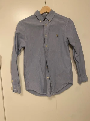 Blå skjorta från Ralph Lauren -  ljusblå skjorta från Ralph Lauren med button-down. Storlek S men passar M också