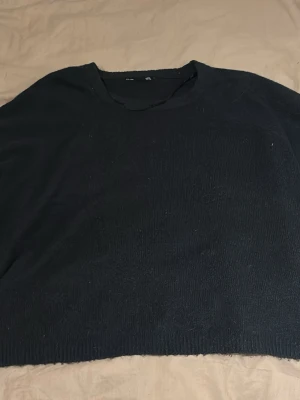 Svart stickad tröja med rund hals kort armad  - En enkel mörkblå  stickad tröja med rund halsringning. Tröjan har korta  ärmar och ribbade muddar vid nederkanten. Perfekt för lager på lager under kyligare dagar.