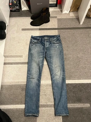 Blå selvedge jeans från NN07 - Säljer ett par snygga blå jeans från NN07 med snygga fades och slitningar. Jeansen har en femficks design, normal passform och raka ben, selvedge. Jeansen har en cool vintagekänsla med små slitningar 