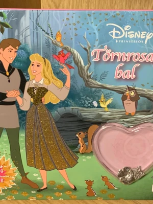 Törnrosas bal Bok med smycke  - Följ Törnrosa när hon får ett vackert halsband av prins Filip och planerar en magisk bal i skogens glänta. Med hjälp av sina vänner och de tre goda feerna vill hon skapa en oförglömlig fest. Perfekt för dig som älskar sagor, vänskap och äventyr!