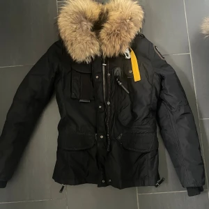 Parajumper Denali Dam jacka S - Jättefin Svart äkta Parajumper jacka med pälskrage och flera fickor. Jackan har en dragkedja och knappar framtill, samt en justerbar dragsko i midjan. På vänster ärm finns en logotyp. Den är i storlek S den är ren, fint skick!säljer pga den inte kommer till användning 🥰pris kan diskuteras!!