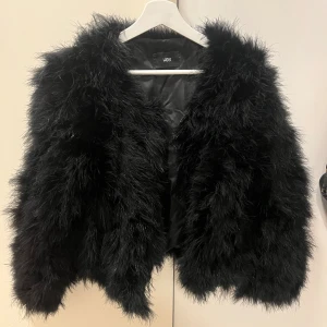 Svart pälsjacka från WOS, stl M - Fluffig svart fjäderjacka från WOS i storlek M. Det är äkta struts fjädrar och helt oanvänd. Om man vill veta mer info är det bara att skriva. Nya friset för denna jacka är 1400kr men säljer för billigare pågrund av att jag köpte den för länge sen.
