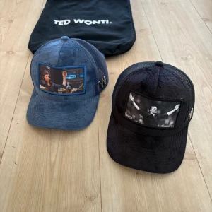 Ted Wonti kepsar med motiv - Två kepsar från Ted Wonti/ sole plus, TikTok företag,,,,!         en i marinblått med färgglatt motiv och en i svart med svartvitt motiv framtill. Båda har mesh på sidorna och ett metallfärgat W på sidan. Materialet är manchester framtill och mesh bak. Snygga detaljer och unik design. Säljs inte längre!  Påsen ingår också!!!