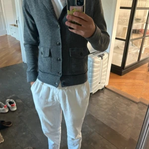 Grå cardigan från Woolrich - Snygg grå cardigan från Woolrich i storlek S/M. Koftan är stickad i ull och har två stora fickor framtill med knappar och en liten metalllogga. Klassisk krage och knappstängning hela vägen. Perfekt för dig som gillar stilrena och bekväma plagg. Också perfekt nu inför hösten. Fint skick. Hör gärna av dig vid frågor eller funderingar. Priset kan diskuteras vid snabb affär🙌🏼