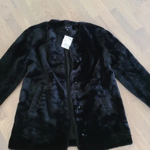 Svart pälsjacka från Zara - Säljer en svart pälsjacka från Zara i storlek M. Jackan har en klassisk rak passform, mjukt fuskpälsmaterial och långa ärmar. Perfekt för dig som vill ha en stilren och trendig look under kyliga dagar.