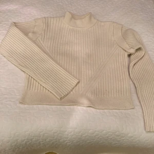 Ribbad beige polotröja från NA-KD - Säljer en ribbad beige polotröja från NA-KD i storlek M. Tröjan har lång ärm, hög hals och är stickad i ett mjukt material. Perfekt för lager-på-lager och passar till allt. Snyggt ribbat mönster som ger en stilren look. Nopprig på ärmarna.