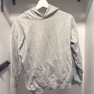 Hoodie med tryck - Grå hoodie med tryck på ryggen. ”Slitaget” på trycket är i designen och är därför inte en reflektion på plaggets skick. 