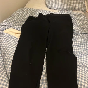 Svarta kostymbyxor från Matinique S - Svarta kostymbyxor från Matinique i klassisk rak modell. Byxorna har bälteshällor, knapp och dragkedja framtill samt två bakfickor. Materialet är en blandning av polyester, viskos och elastan för en skön känsla och snygg passform.