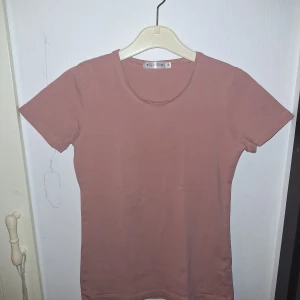 Rosa t-shirt - En enkel och stilren rosa t-shirt från Joy of Love i storlek XS men skulle snarare säga att den är storlek S/M. T-shirten har rund halsringning och korta ärmar. Tillverkad i mjukt bomullsmaterial som känns skönt mot huden. Perfekt för en chill och avslappnad look.