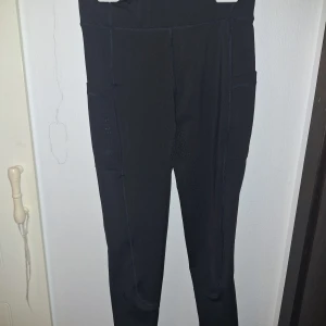 Svarta ridleggings från Copperfield - Svarta ridleggings från Copperfield med hög midja och smarta fickor på sidorna. Byxorna är helskodda. Tillverkade i stretchigt syntetmaterial för maximal rörelsefrihet. Helt oanvända!