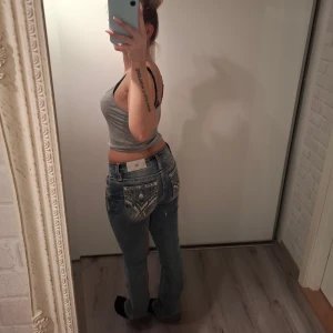 Miss me bootcut jeans  - Säljer ett par Miss me jeans med snygga slitningar och kontrastsömmar. Bakfickorna har coola broderade detaljer och knappar. Jeansen har låg midja och klassisk femficksdesign. Perfekta för dig som gillar en avslappnad men ändå trendig look.