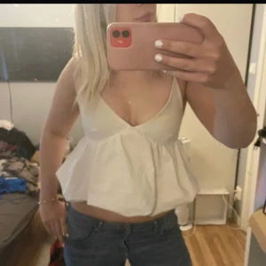 Vit croppad linnetopp med v-ringning från Zara  - Säljer en söt vit croppad linnetopp med djup v-ringning och tunna axelband. Toppen har en luftig, voluminös passform nedtill och är perfekt för varma dagar. Enkel och stilren design som är lätt att matcha med jeans eller kjol.