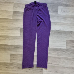 Lila prickiga leggings stl 140 - Mysiga lila leggings med små prickar i hela tyget. De har resår i midjan och är gjorda i ett mjukt, stretchigt material som passar perfekt för chill eller träning. 