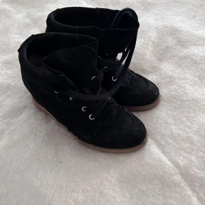 Isabel Marant liknande skor - Knappt använda snygga svarta sneakers med högt skaft och snörning. Skorna har rund tå och platt sula i beige, samt metallöglor för snörena. Materialet ser ut att vara mocka eller syntet, vilket ger en cool och urban känsla. Knappt använda max 3 gånger!