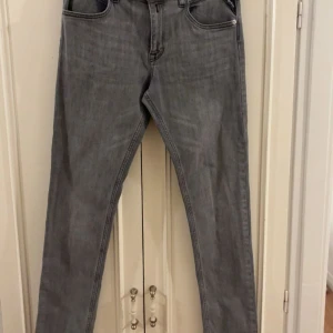 Grå Replay jeans straight fit - Snygga grå jeans från Replay med klassisk femficksdesign och raka ben. Jeansen har svarta detaljer på bakfickorna och Replay-logga vid myntfickan. Tillverkade i mjukt jeanstyg som sitter skönt hela dagen.