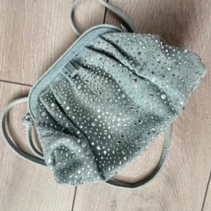 Blå clutch väska med paljetter - Supersöt liten blå axelväska med glittriga paljettdetaljer och mjukt jeans tyg. Väskan har en klassisk form med rynkade detaljer och lång axelrem, perfekt för att bära över axeln eller i handen. Ger en extra touch till din outfit!