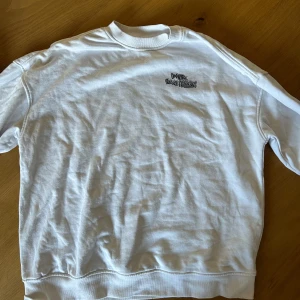 Vit sweatshirt från Comtex med tryck - Vit sweatshirt från Comtex med coolt tryck på ryggen i svart, rosa, blått och orange. 