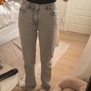 Gråa stright jeans med mid waist - Säljer ett par ljusgrå jeans i mid waist straight fit. Jeansen har klassisk femficksdesign, dragkedja och knapp framtill. Materialet är denim och passformen är avslappnad med raka ben. Perfekta för en chill och trendig look. Jätte skönt jeans material säljer då de inte används längre🍁🍁