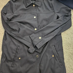 Svart rock från Zara Basic, storlek S - Snygg marinblå rock från Zara Basic med klassisk krage och guldfärgade knappar. Jackan har två fickor framtill och är långärmad. Perfekt för dig som gillar stilrena och enkla plagg med en clean look.