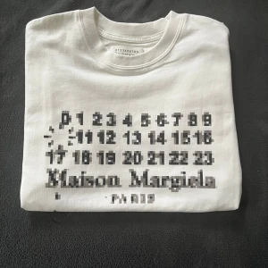 Vit Maison Margiela t-shirt pixlig  - Säljer denna feta T-shirt från Maison Margiela 🤩Storleken är 46 (M/L). Tröjan är vit med en fet pixlig version av den klassiska Maison Margiella loggan 🙌Till tröjan medföljer påsen. Vid minsta fråga eller fundering är det bara att skriva ✍️ 