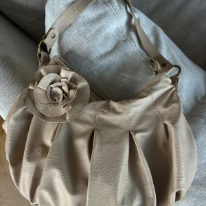 Väska  - Jätte fin vintage väska i beige med stor ros. Rymmer mycket. Köpt från Vintage & Friends. Liten fläck på rosen. 