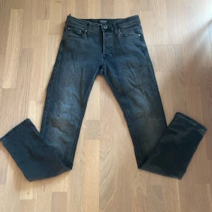 Jack & Jones Slim Glenn svarta jeans - Snygga svarta jeans från Jack & Jones, modell Slim Glenn. Jeansen har en slim passform, klassisk femficksdesign och är tillverkade i stretchig denim för extra komfort. Perfekta för dig som gillar en smal siluett och stilren look.
