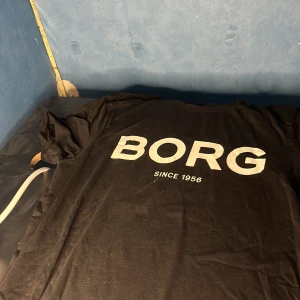 Svart Björn Borg t-shirt med tryck - Svart t-shirt från Björn Borg med stort vitt BORG-tryck och texten 'Since 1956' på bröstet. Klassisk passform och rund hals. Perfekt för en sportig och avslappnad stil.