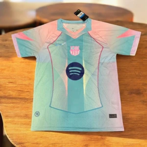Barça x Nike pastell fotbollströja - Snygg FC Barcelona fotbollströja från Nike i pastellfärger med klubbmärke och Spotify-logga på bröstet. Tröjan har korta ärmar, V-ringning och är tillverkad i lätt, ventilerande funktionsmaterial. Färgskalan går i ljusblått, rosa och mintgrönt med grafiska detaljer.