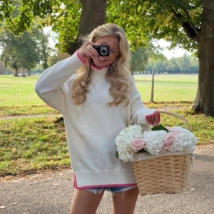 Vit stickad tröja med rosa detaljer - Storlek S/M, jag är 170cm som referens. Finns även en liten fläck på baksidan, köpt på Vinted men aldrig använd av mig. Helt ny med prislapp