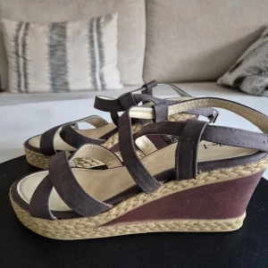 Kilklackar * Bruna * Storlek 38 - * Eleganta bruna sandaler med kilklack.  * Bekväma och stilrena. * Använd max två ggr. * Skomått bland foton. * Mycket bra skick. Hittar inga fel.  Djur och rökfritt hem. Se bilder och förstora då de ingår i beskrivningen. Se gärna mina övriga annonser.   Vid avhämtning finns de i Sollentuna.