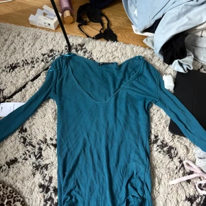 Blå ribbad långärmad klänning - Säljer en blå ribbad klänning med lång ärm och v-ringad hals. Klänningen har en kroppsnära passform och är tillverkad i ett stretchigt material som sitter snyggt. Perfekt för dig som gillar enkel men stilren design.