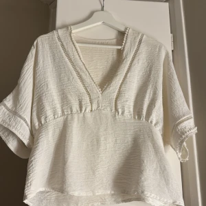 Vit blus med v-ringning och spetsdetaljer - Säljer en vit blus med v-ringad hals och korta ärmar.⭐️⭐️