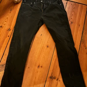 Svarta Levi's 511 jeans - Säljer ett par svarta Levi's 511 jeans med klassisk femficksdesign och dragkedja. Jeansen har en slim passform och raka ben, tillverkade i slitstarkt jeanstyg. Perfekta för dig som gillar en stilren look med snygga detaljer.