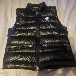 Moncler väst - Fräsch Moncler väst i storlek M! Västen är i bra skick! Enda problemet är det lilla hålet på framsidan som visas i bild 3! Västen passar dig som är 170-175cm lång!