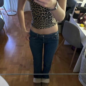 Levis low waist bootcut jeans blå - Mörkblå jeans från Levis med låg midja och bootcut-modell. Klassisk femficksdesign och raka ben med lätt utsvängning nertill. Jeansen är i ett robust denimtyg och har Levis-logga på bakfickan. Liten vit fläck på vänster benet men inget som syns mycket alls.