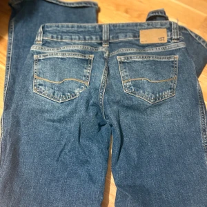 Blå jeans med slitna detaljer 157 - Snygga blå jeans från 157 med slitna hål på båda knäna och klassisk femficksdesign. Jeansen har en rak passform och är tillverkade i jeansmaterial med ljus tvätt och kontrastsömmar. Perfekt för dig som gillar en avslappnad och trendig look.