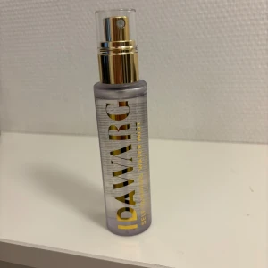 IDAWARG Self-Tanning Water Mist - Transparent ansiktsmist från IDAWARG med guldiga detaljer och sprayfunktion. Ger en fräsch och solkysst look med enkel applicering. Perfekt för dig som vill ha en naturlig bränna utan sol. Kommer i en smidig plastflaska. Endast testad en gång! 