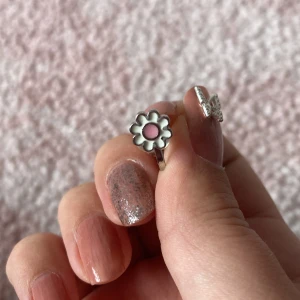 Söt clipsörhänge med blomma i silver och rosa - Supergullig clipsörhänge i silverfärgat material med en blomformad detalj. Blomman har vit kant och rosa mitt, vilket ger en lekfull och trendig vibe. Perfekt för dig som gillar att sticka ut med accessoarer som har lite extra personlighet.