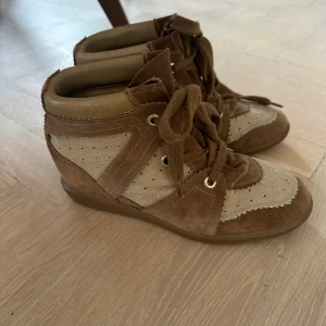 Isabel Marant bruna sneakers i mocka - Snygga Bobby sneakers från Isabel Marant i brunt och beige med coola detaljer i mocka och textil. Skorna är i jättefint skick! Passar dig som gillar en avslappnad men trendig stil.