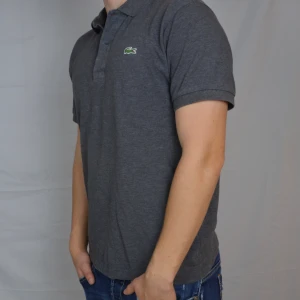 Lacoste Piké  - Snygg grå piké från Lacoste i storlek 3, motsvarar medium. Pikén är i gott skick och har inga defekter. Vid frågor eller funderingar är det bara att höra av sig, och kom ihåg, alltid 14 dagars ångerrätt hos oss på Revalo!