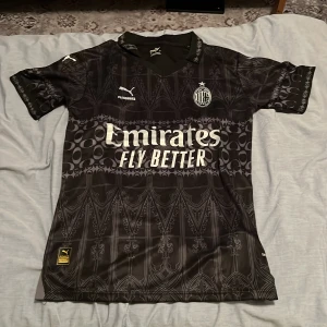 AC Milan x Puma svart fotbollströja S - AC Milan fotbollströja i svart med gråa detaljer och grafiskt mönster. Passar någon som är cirka 175-180 